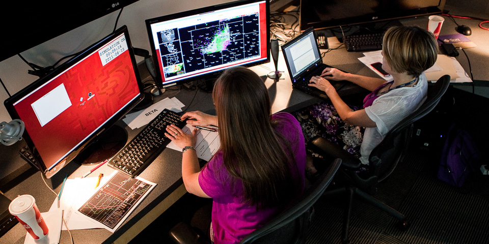 Two researchers working side by side. One researcher is interacting with a radar display; the other is typing into a laptop